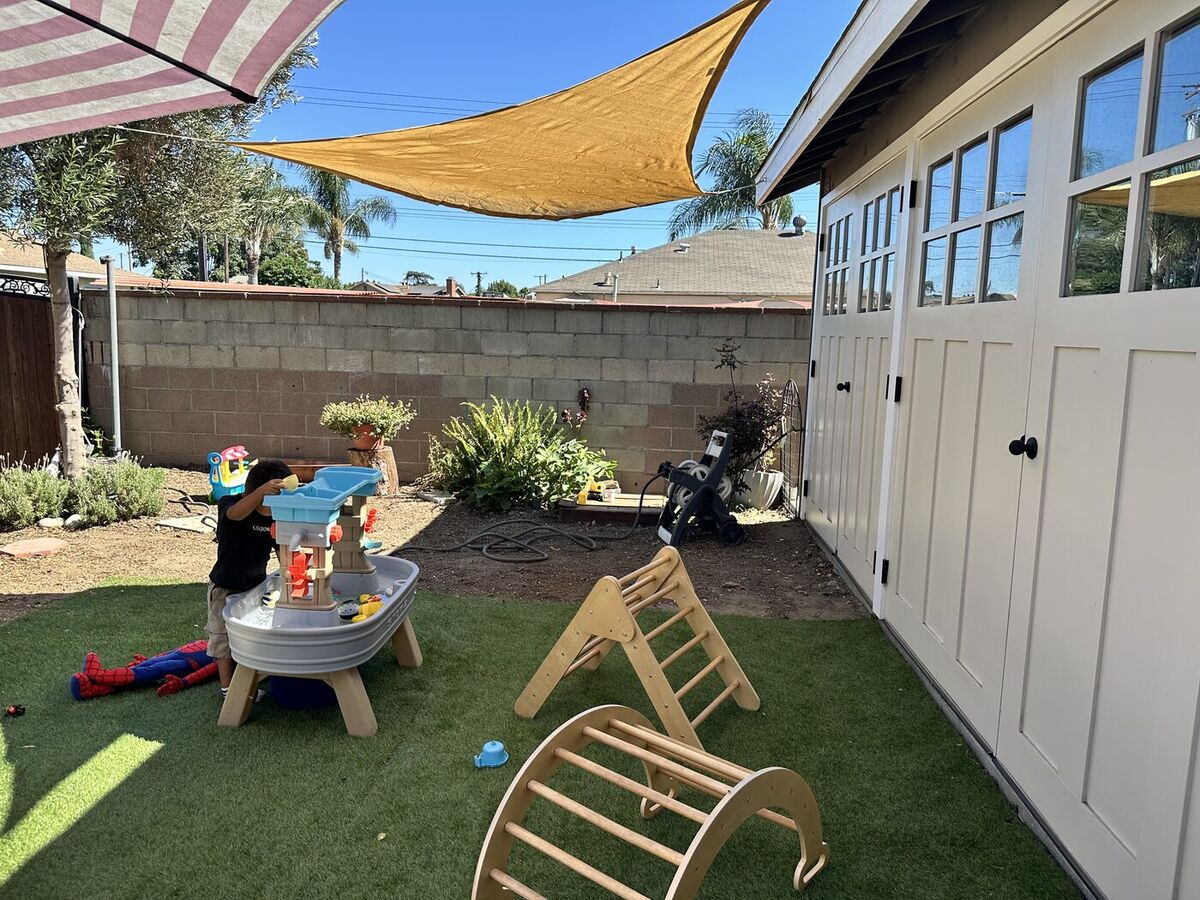Our shaded backyard with water table and wooden climbing gym