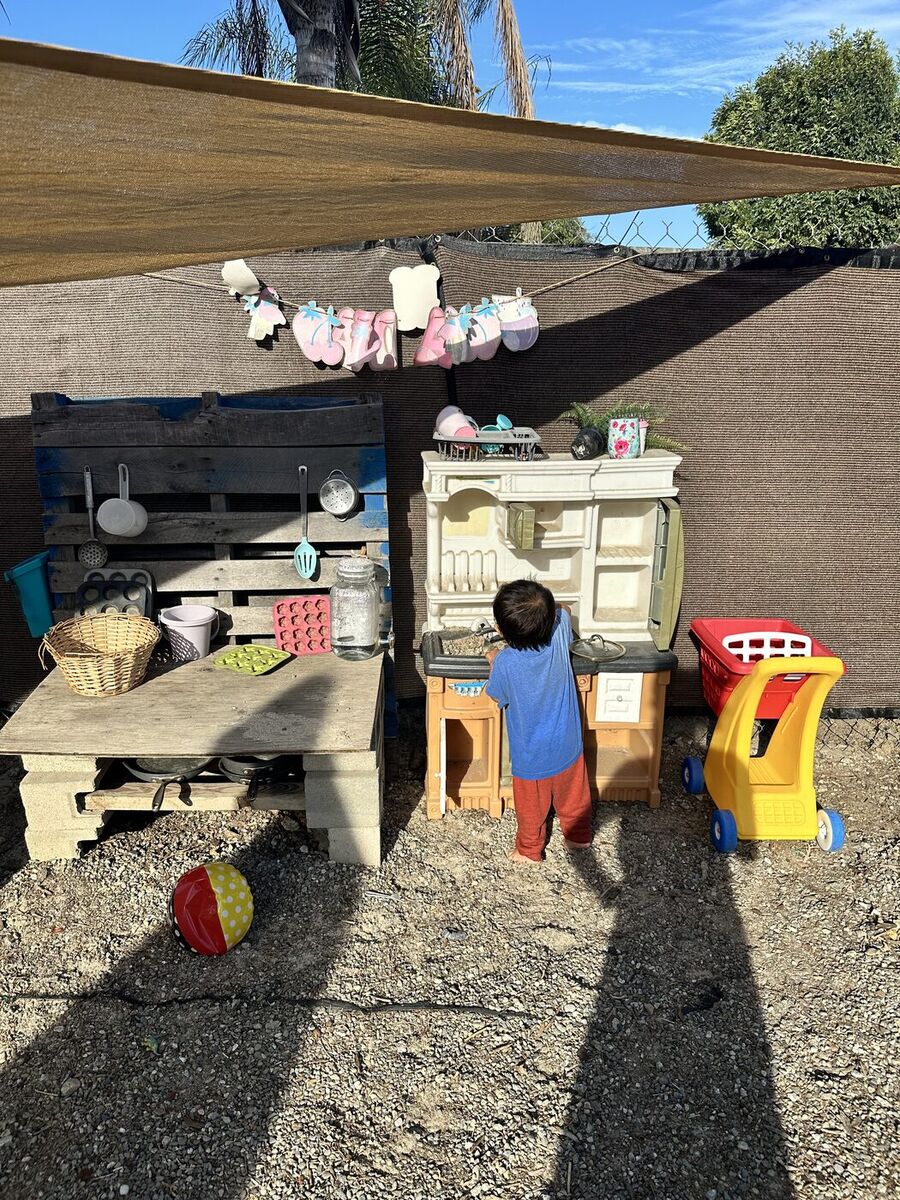 A child cooking at the outdoor mud kitchen