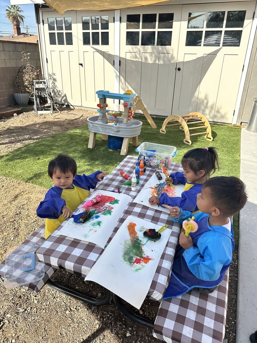 Children painting at an outdoor table