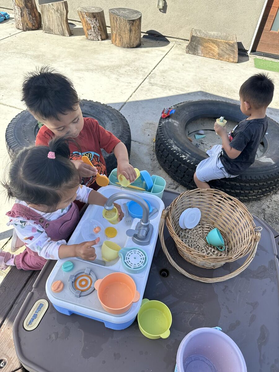 Children washing dishes at the outdoor water play kitchen